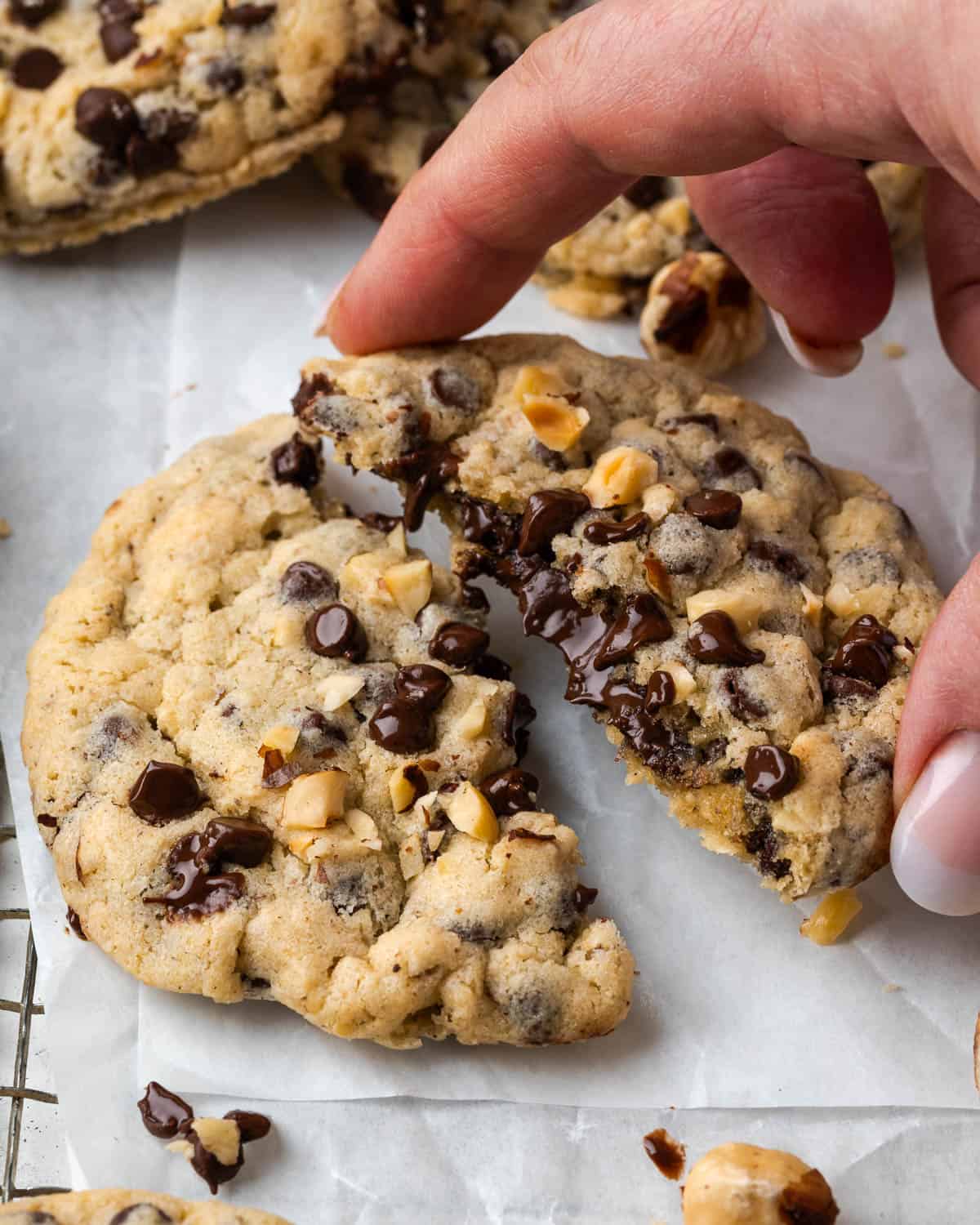 A hand grabbing half a Nutella stuffed cookie showing the melted chocolate inside.