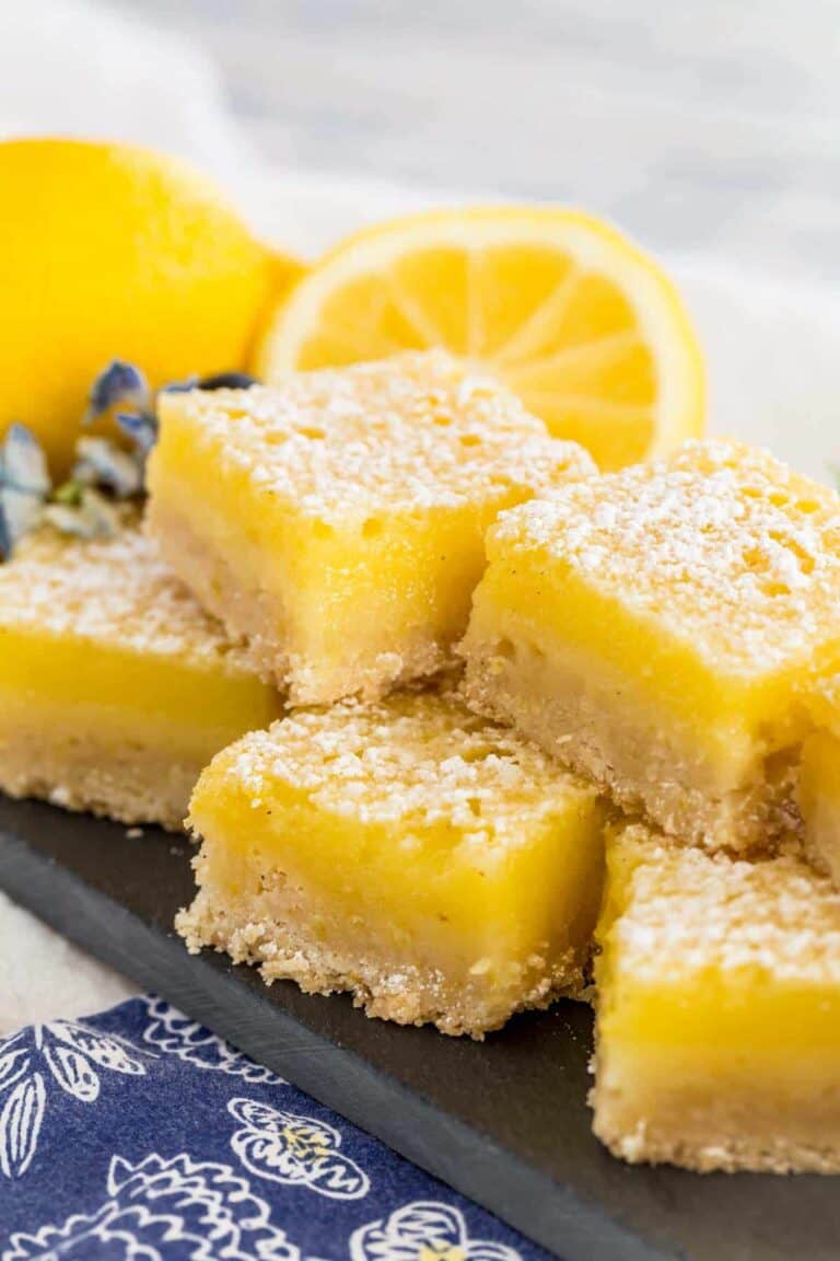 Several gluten free lemon bars stacked on a plate.