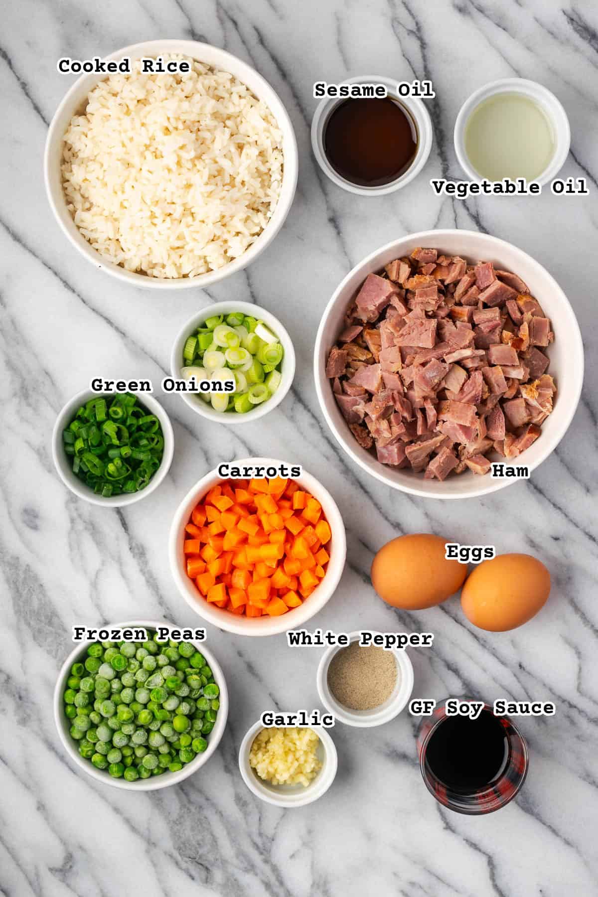 Ingredients for ham fried rice on a marble countertop. 