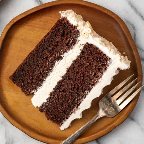 A slice of chocolate coconut cake served on a wooden plate.
