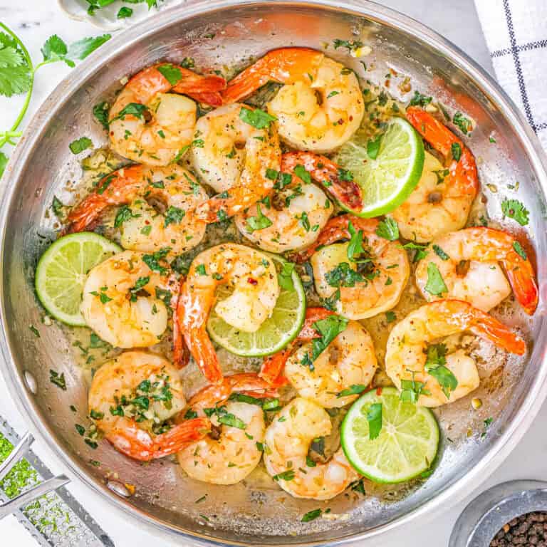 Cilantro lime shrimp served in a large skillet with slices of fresh lime.