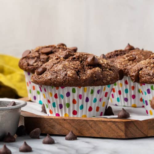 Several gluten free chocolate muffins sitting on a wood tray.