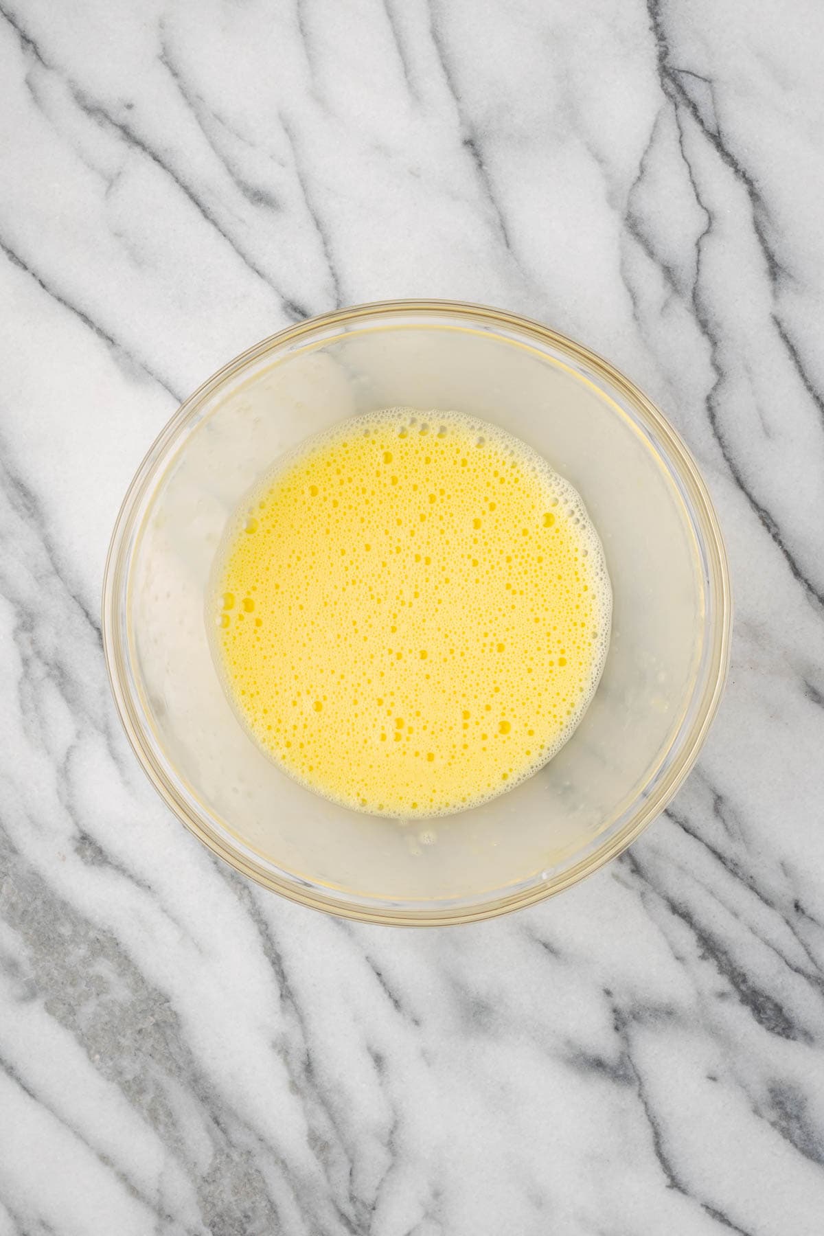 Two eggs beaten in a small glass bowl. 