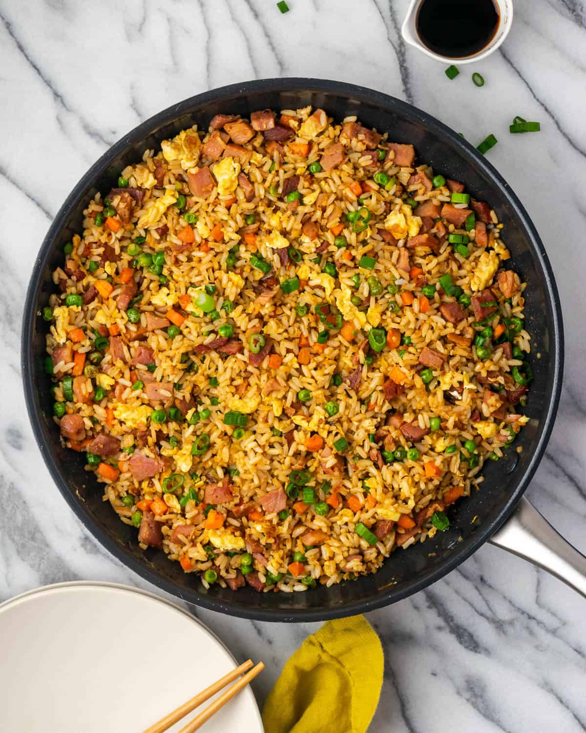 A pan of freshly cooked ham fried rice sitting on a marble counter. 