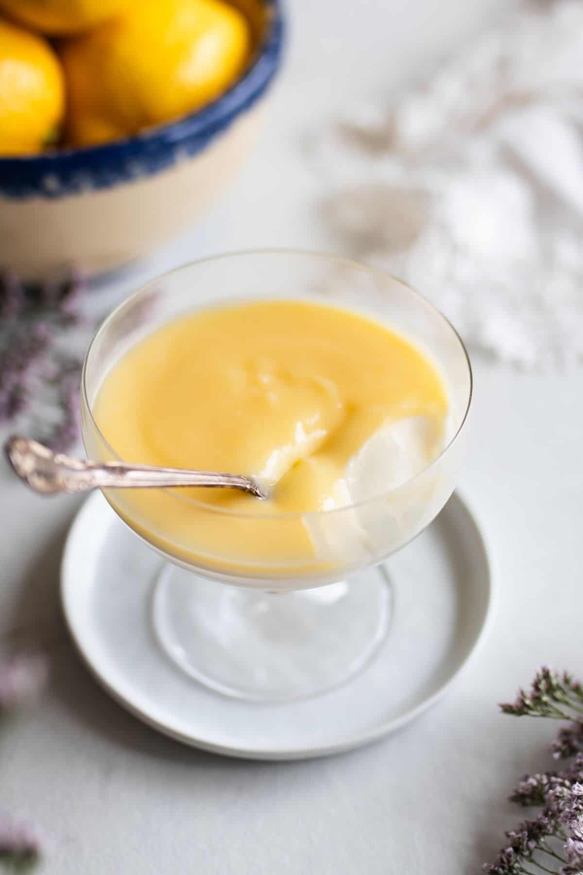 A spoon scooping a bite from a glass of lemon panna cotta.