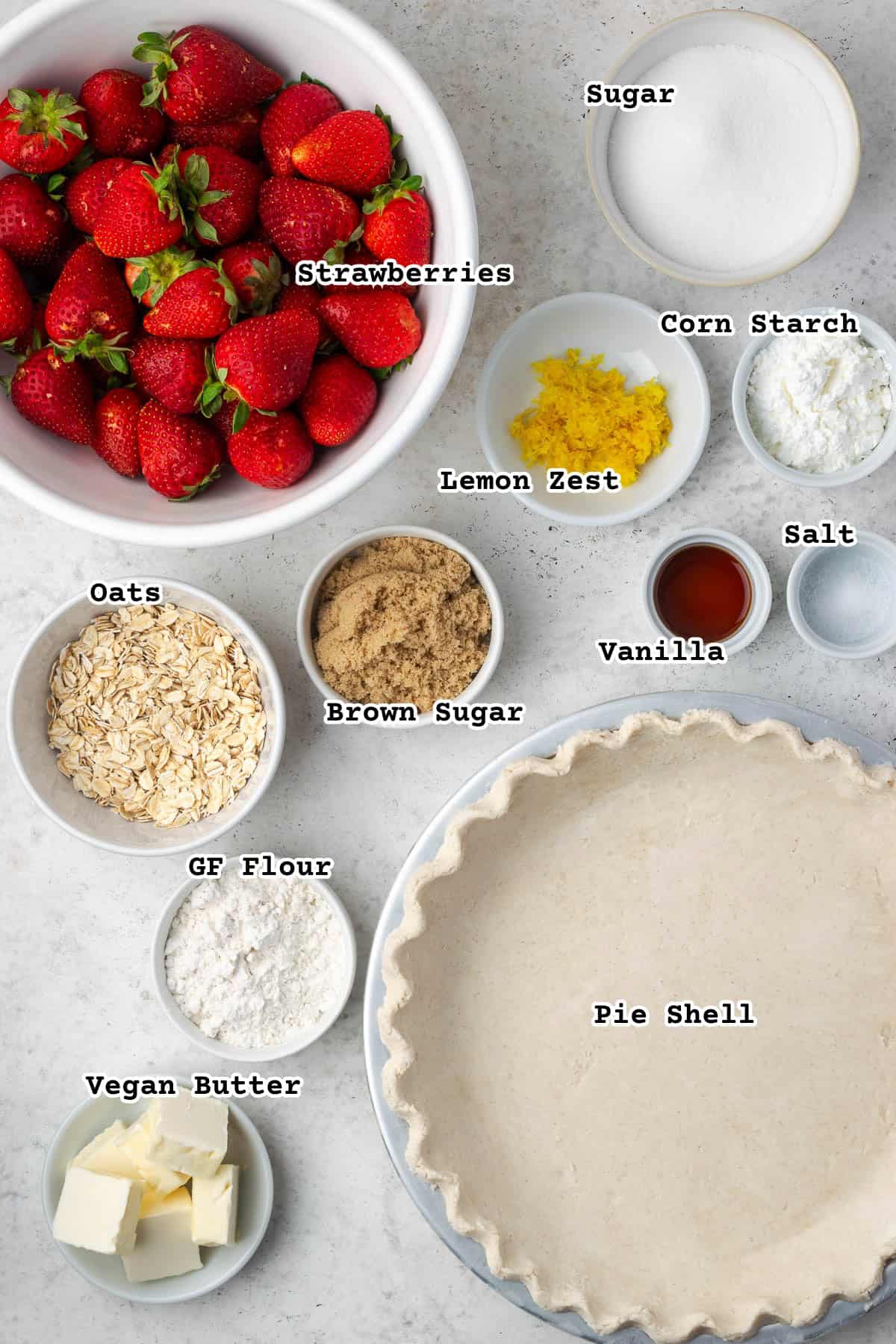 Ingredients for a strawberry crumble pie sitting on a white counter.
