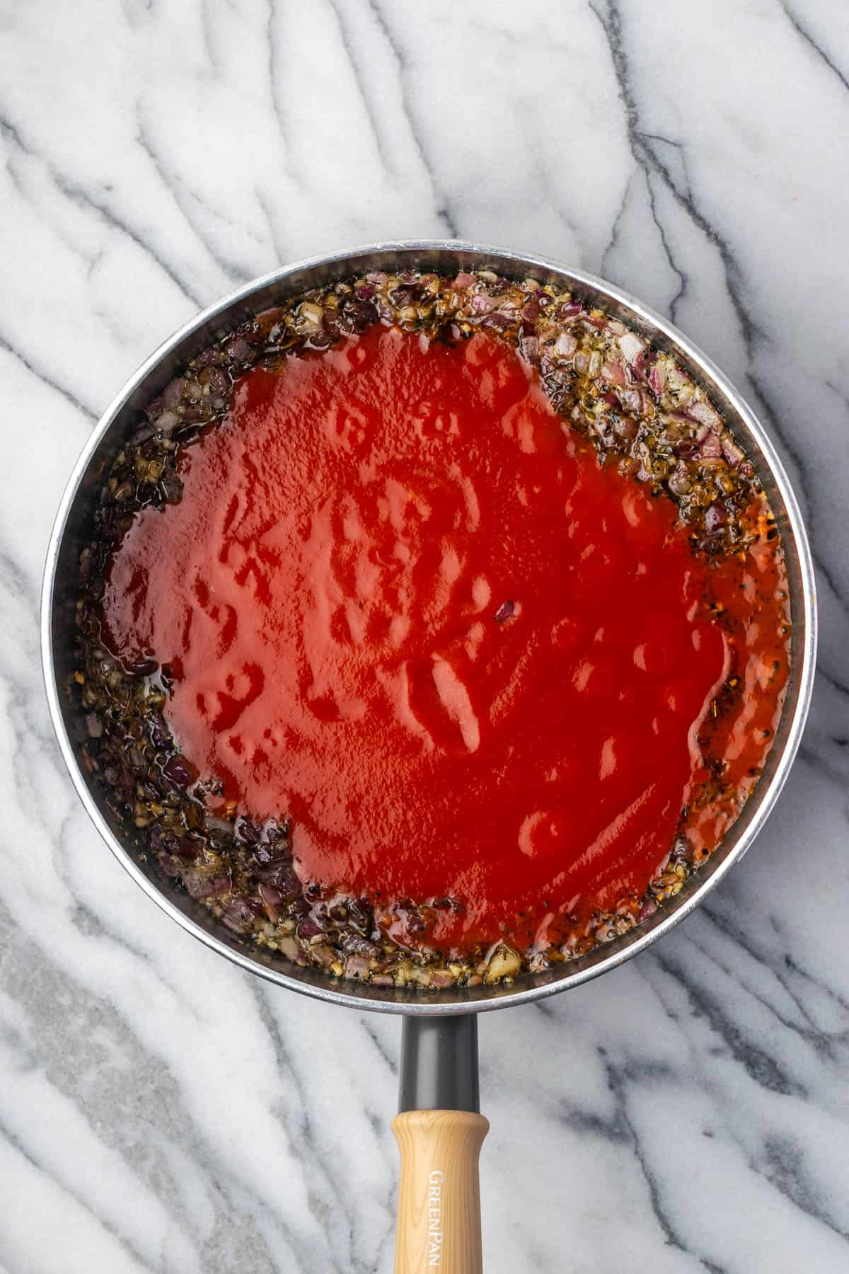 Tomato sauce poured into the sauce pan with the cooked vegetables.