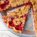 A slice of strawberry crumble pie sitting in a metal pie tin.