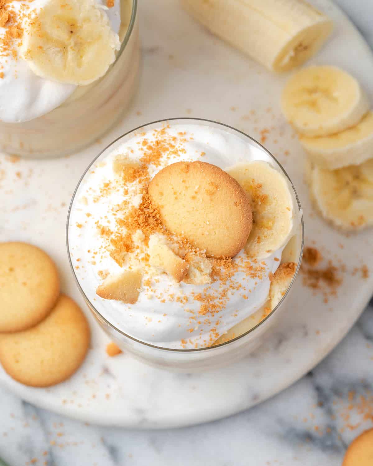 A single serving of gluten free banana pudding topped with whipped cream and vanilla wafers. 