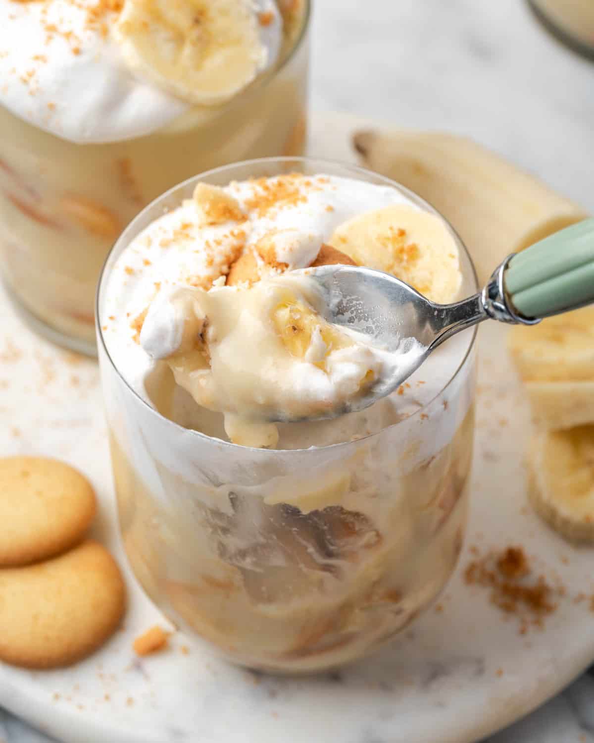 A spoon scooping a bite of banana pudding from a serving glass.