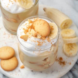 Two glasses of gluten free banana pudding sitting on a marble tray.