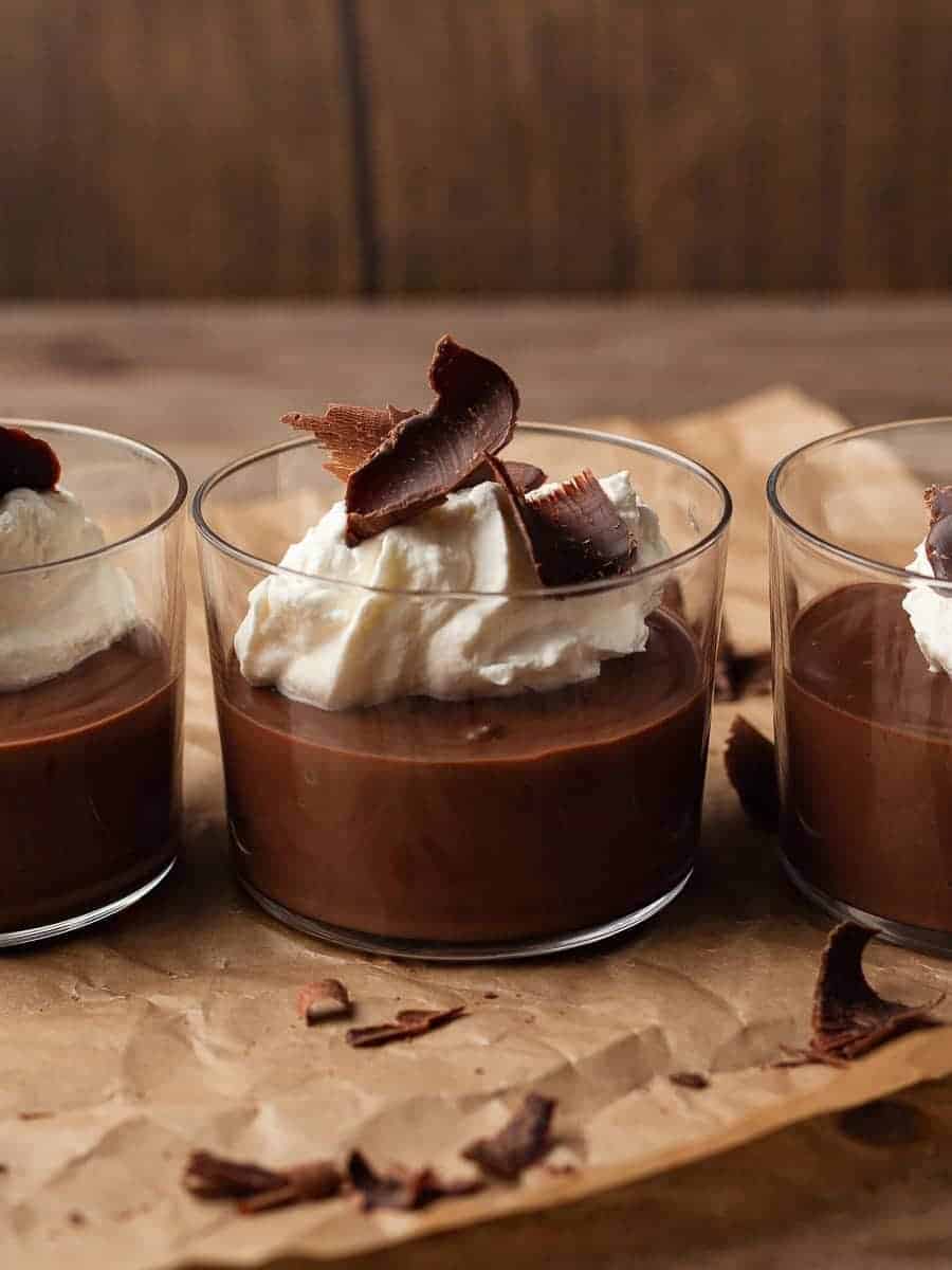Three glasses of chocolate pudding topped with whipped cream.