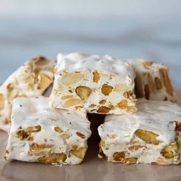 Several squares of Italian nougat stacked on a table. 