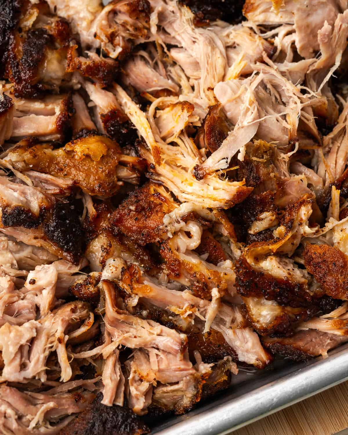 A tray of pulled pork sitting on a wooden cutting board.