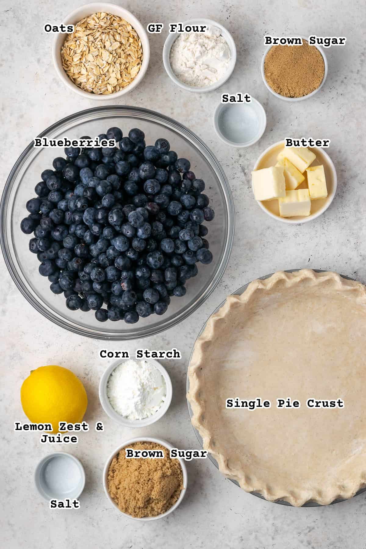 Ingredients for a blueberry crumble pie sitting on a white countertop.