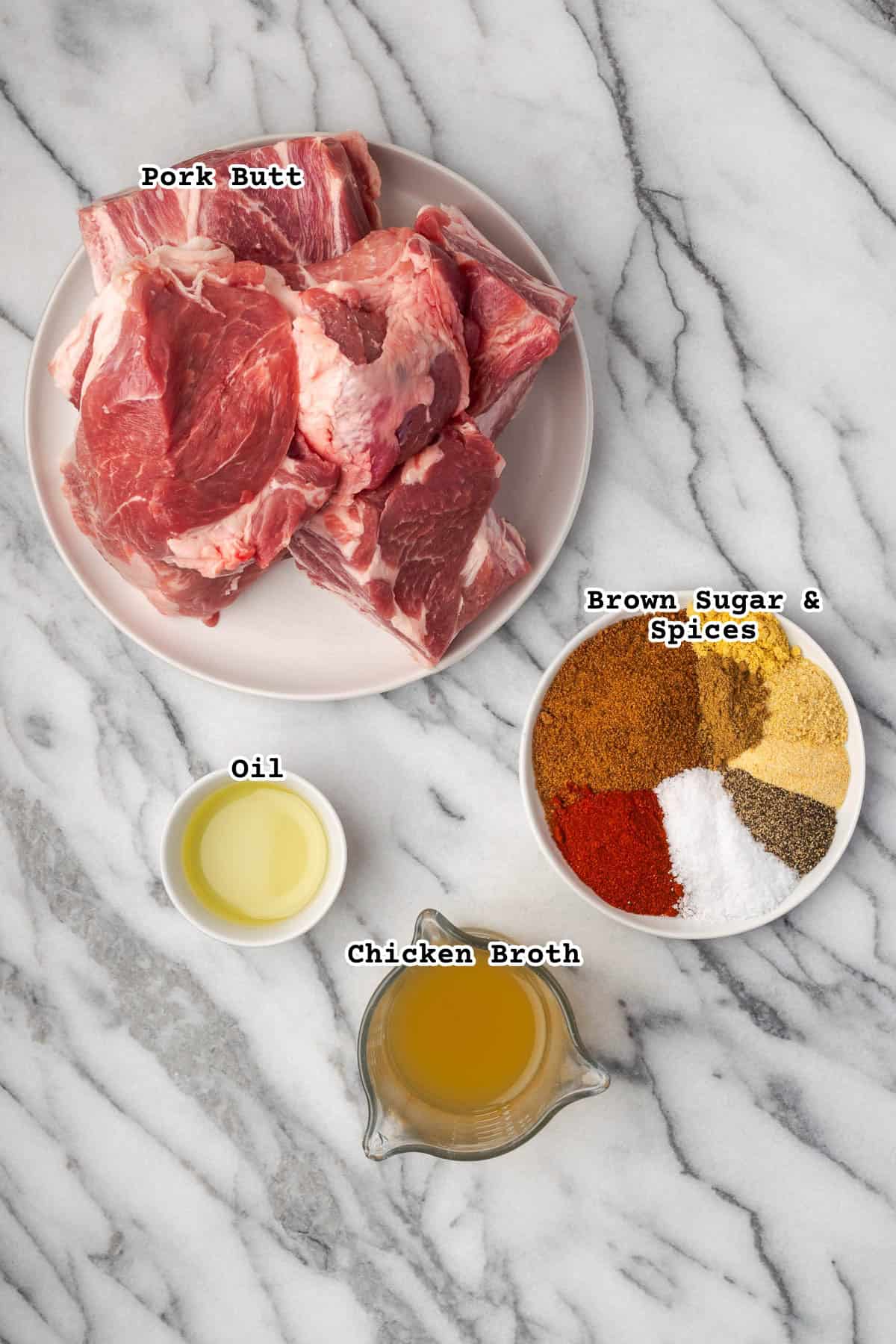 Raw pork butt and ingredients for a spice rub sitting on a marble countertop. 