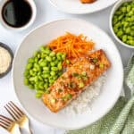 A teriyaki salmon rice bowl with edamame and carrots.