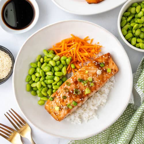 A teriyaki salmon rice bowl with edamame and carrots.