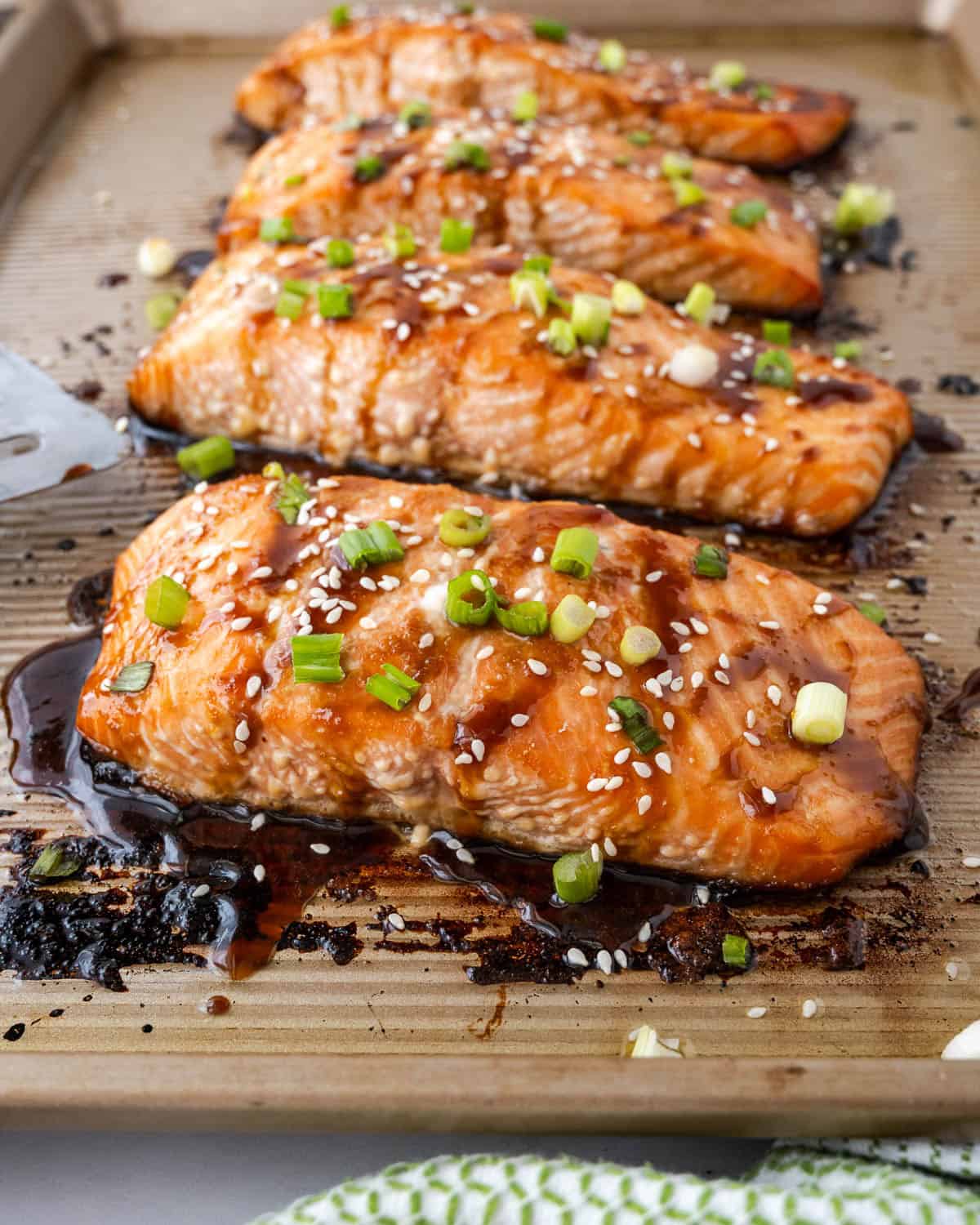 Four baked salmon filets coated with teriyaki sauce, green onions and sesame seeds.