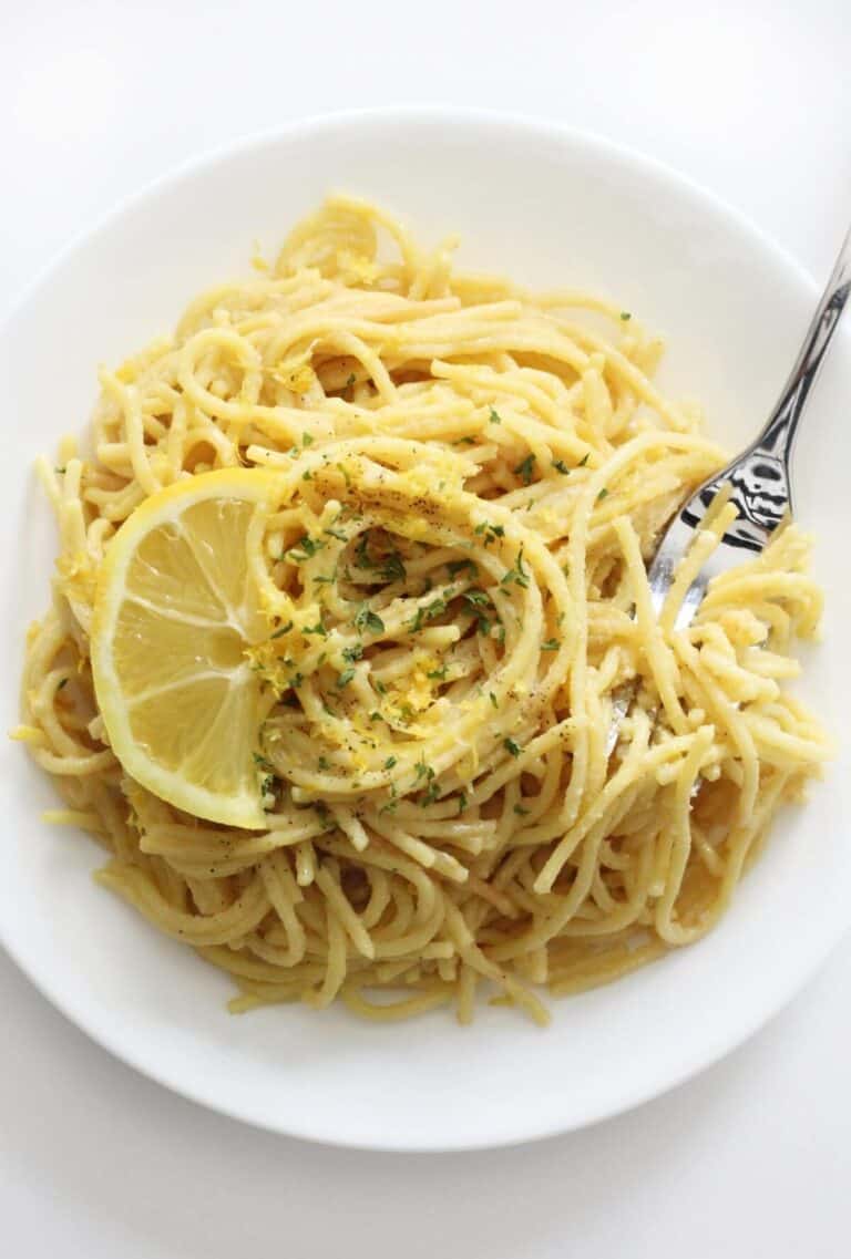 A plate of gluten free pasta topped with a fresh lemon slice.