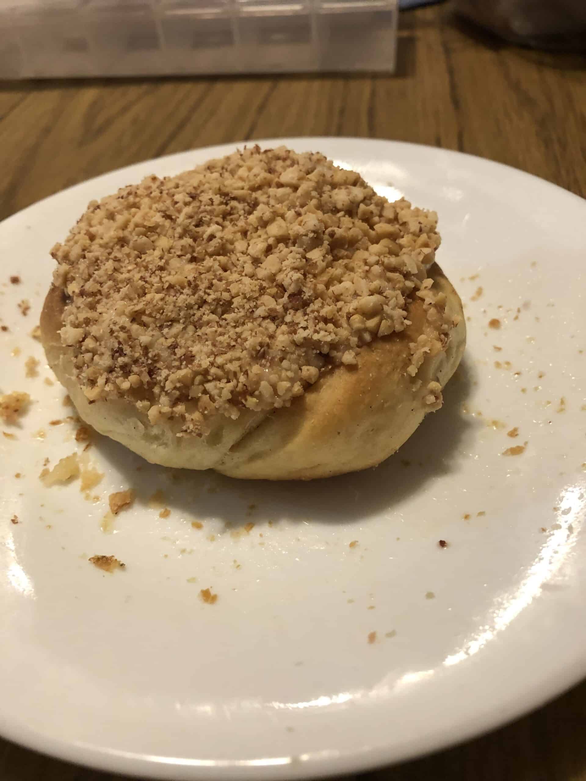 A butter roll topped with butter icing and nuts.
