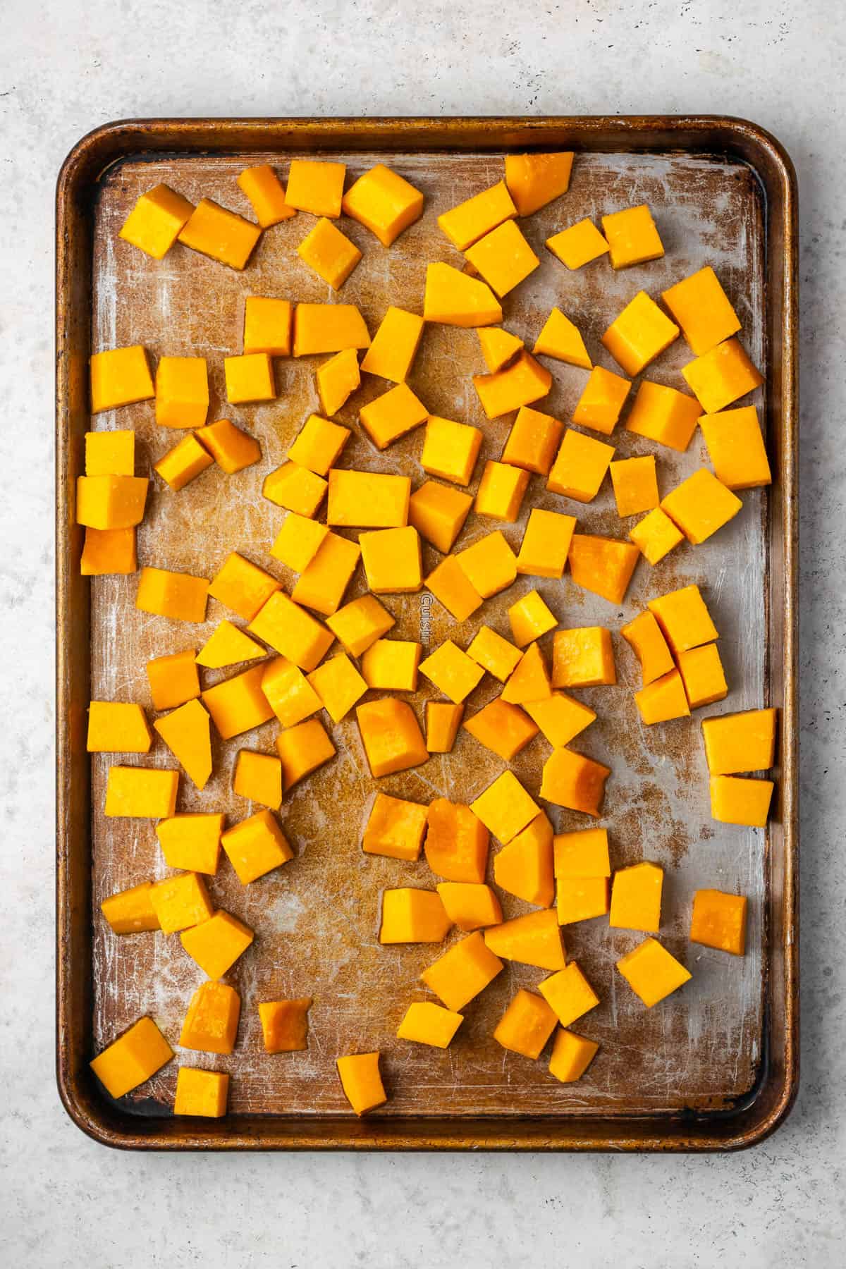 Butternut squash cubes spread on a baking sheet.