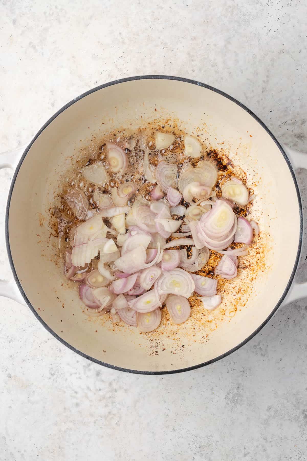 Sliced shallots added to the pot with the reserved bacon grease.