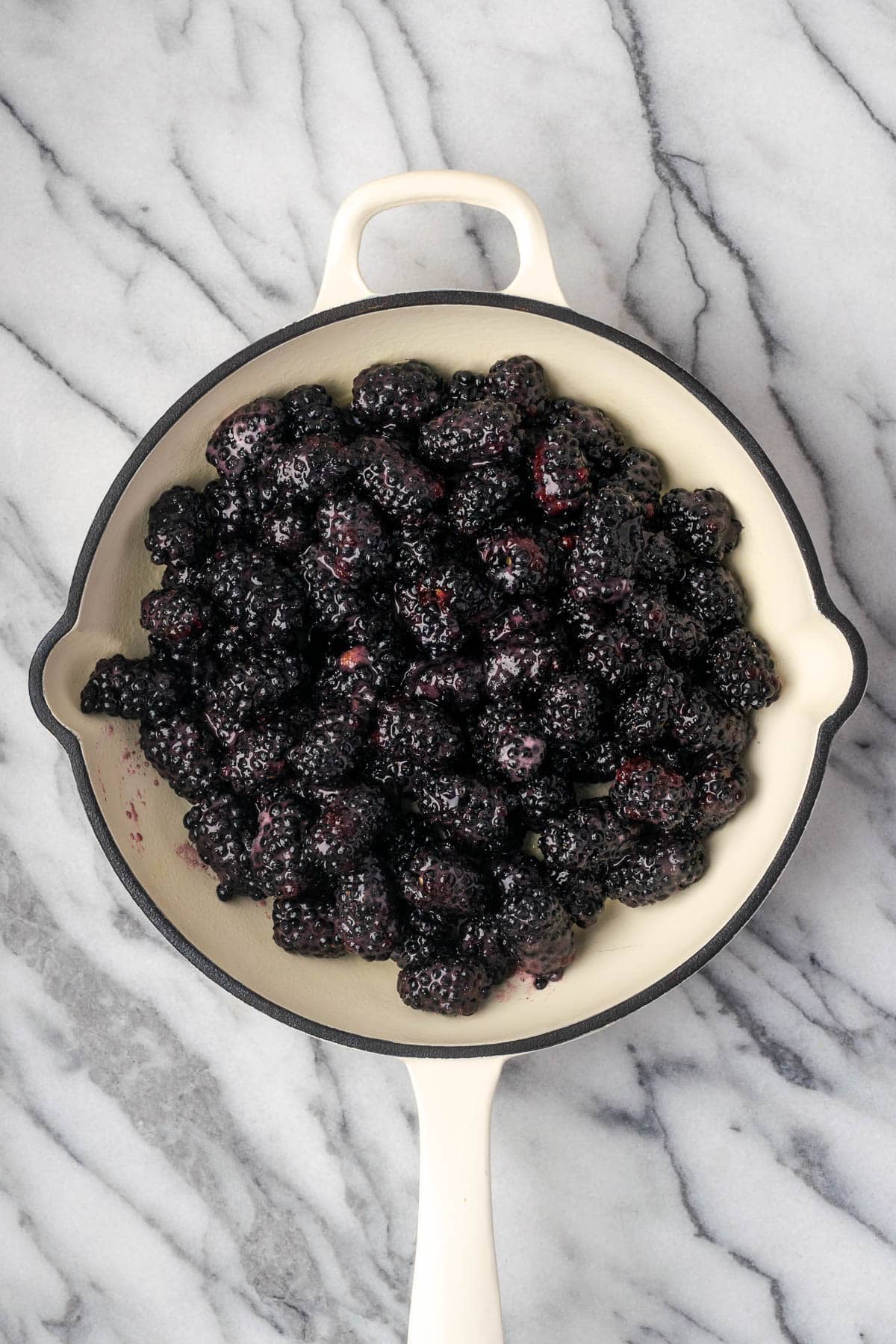 Blackberry cobbler filling spread in a cast iron skillet.
