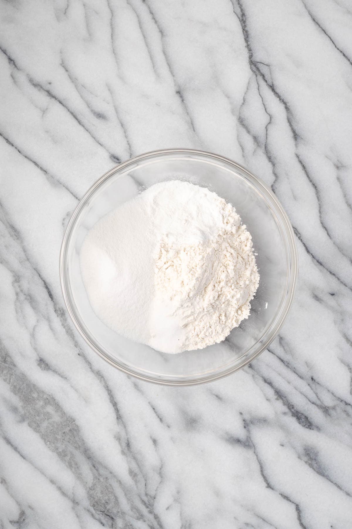 Gluten free flour, sugar, baking powder, and salt combined in a glass mixing bowl. 
