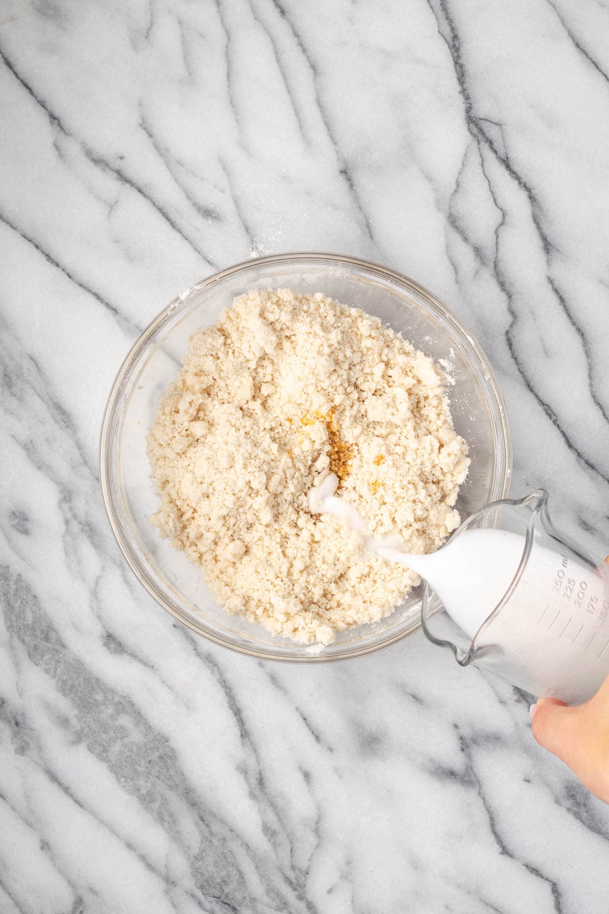 Milk being poured into the bowl of dry ingredients.