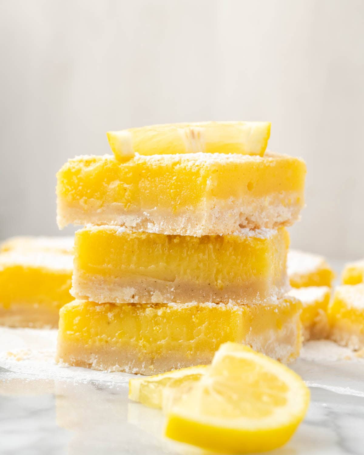 Three gluten free lemon bars stacked on a marble counter.