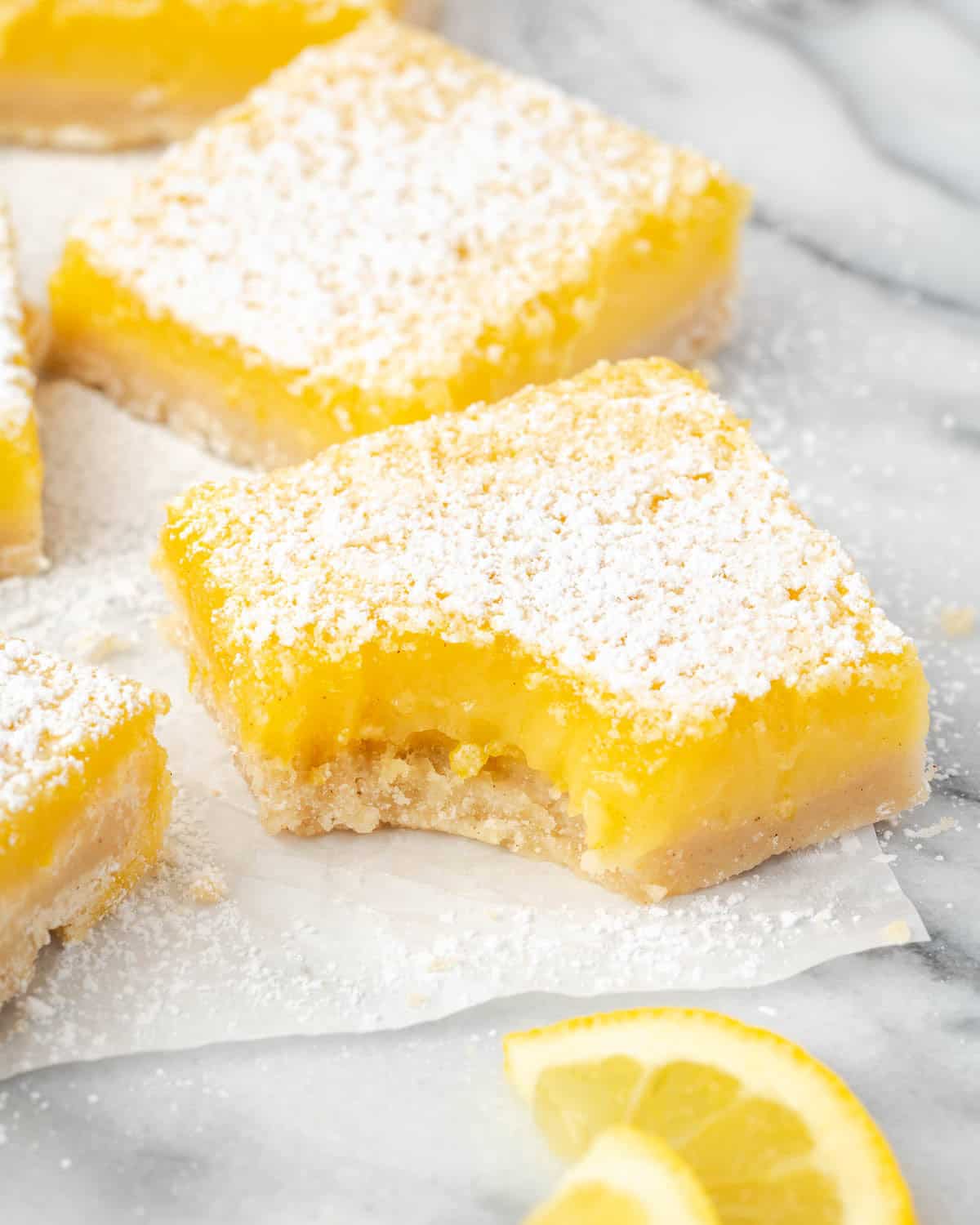 A single gluten free lemon bar with a bite take out. 