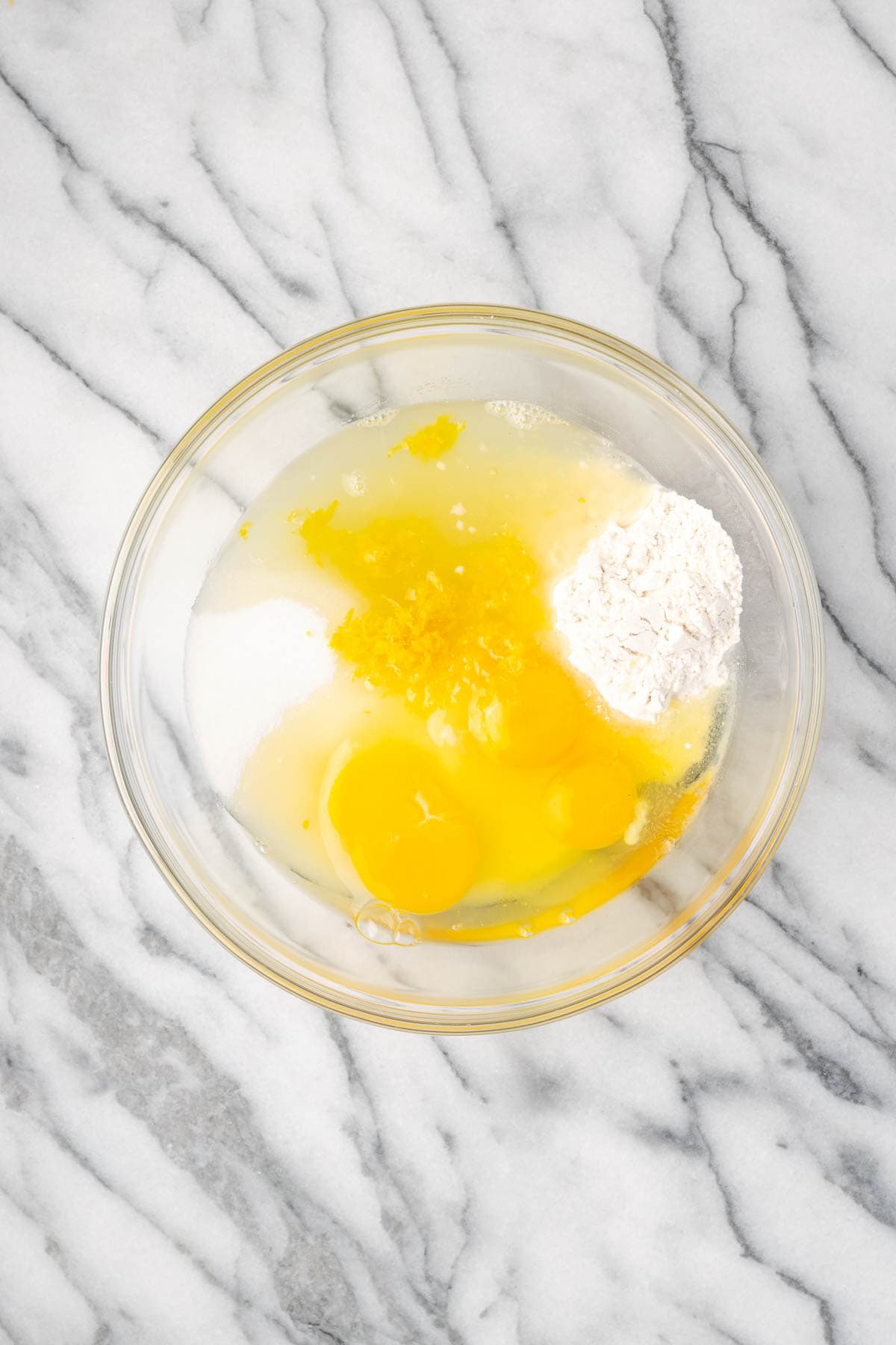 Eggs, sugar, lemon juice, lemon zest, and flour combined in a large mixing bowl. 