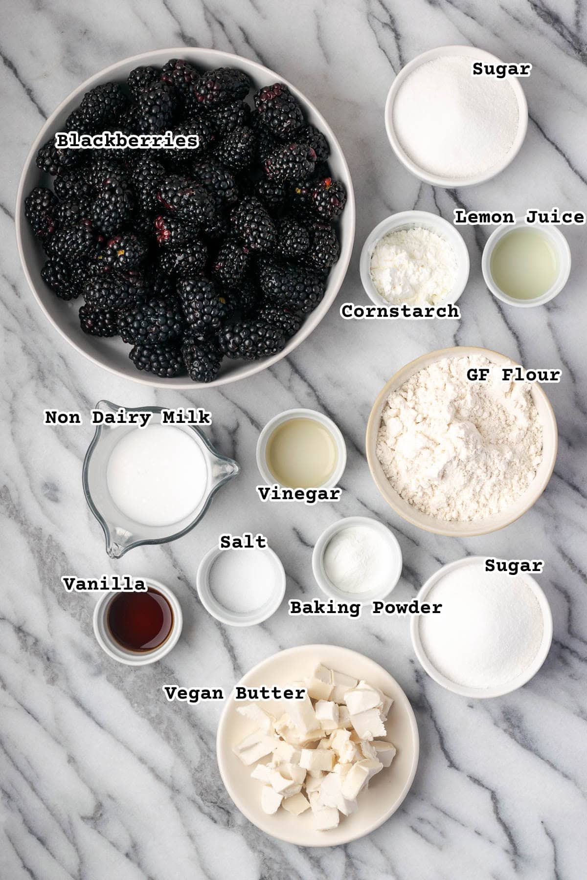Ingredients for a gluten free blackberry cobbler sitting on a marble counter.