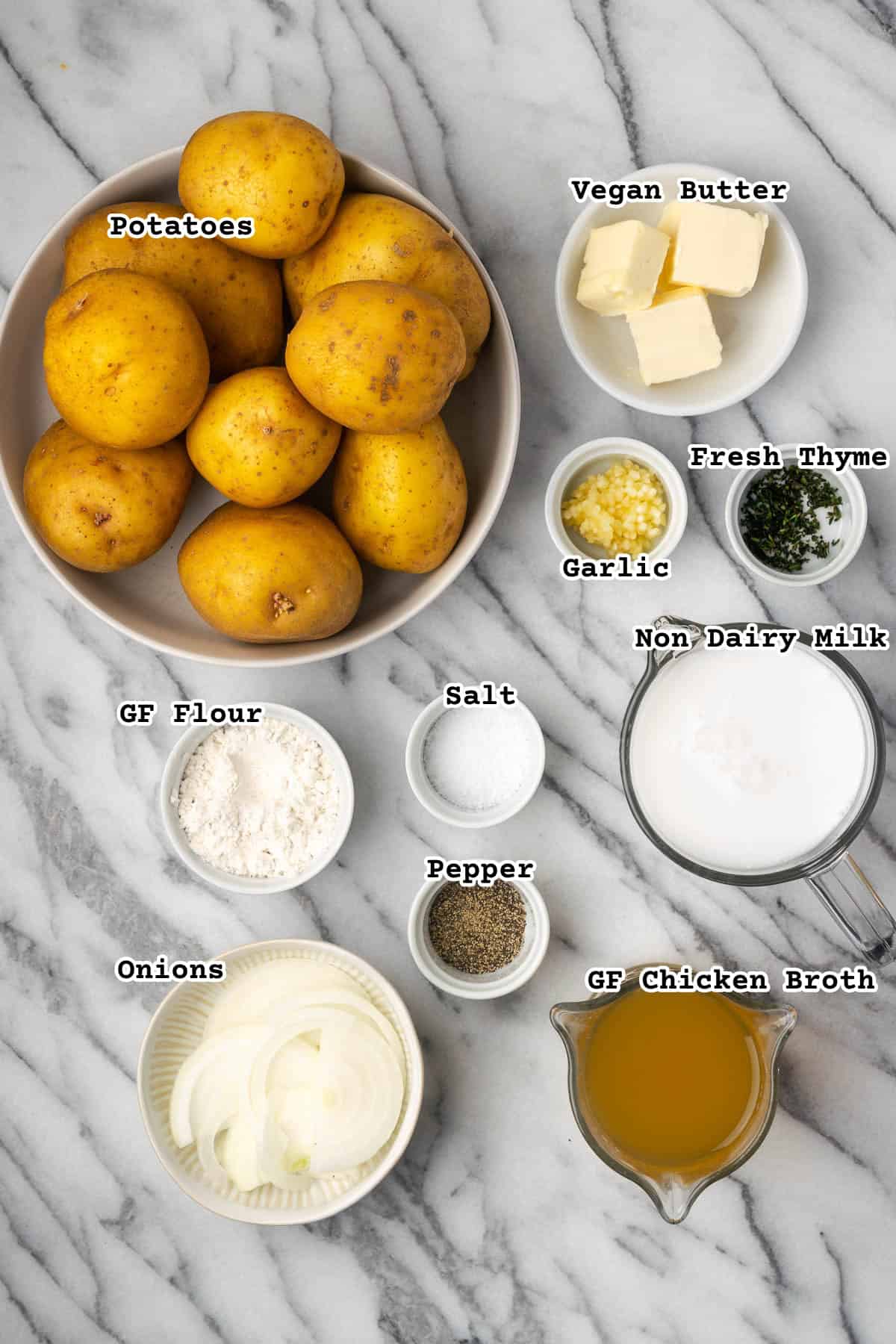 Ingredients for gluten free scalloped potatoes on a marble counter.