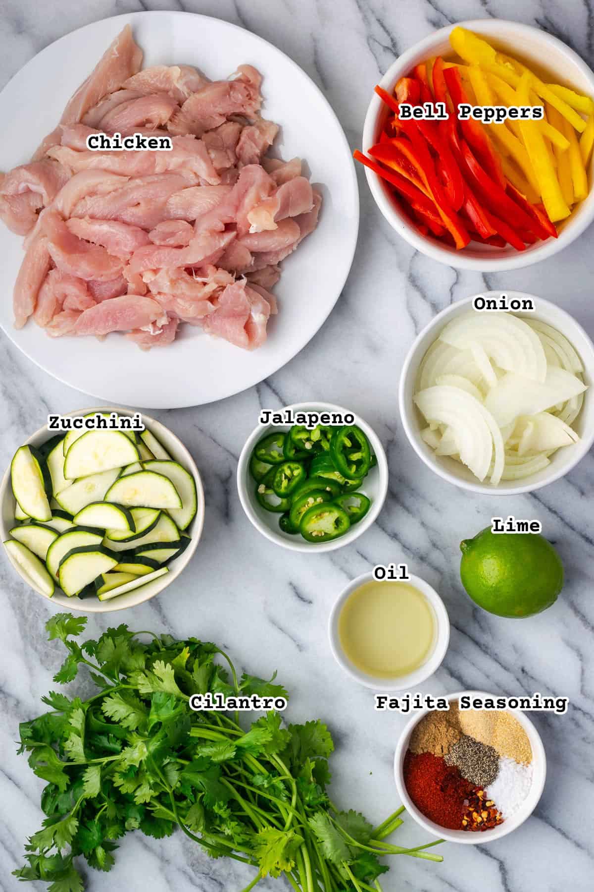 Ingredients for sheet pan chicken fajitas sitting on a marble counter.