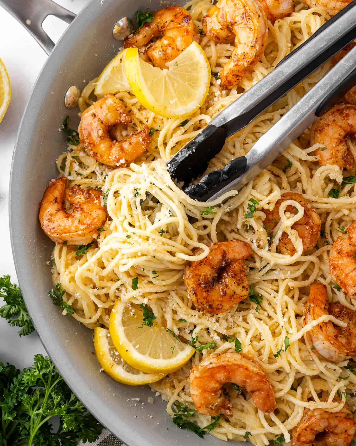 A pair of tongs tangled in a dish of gluten free pasta.
