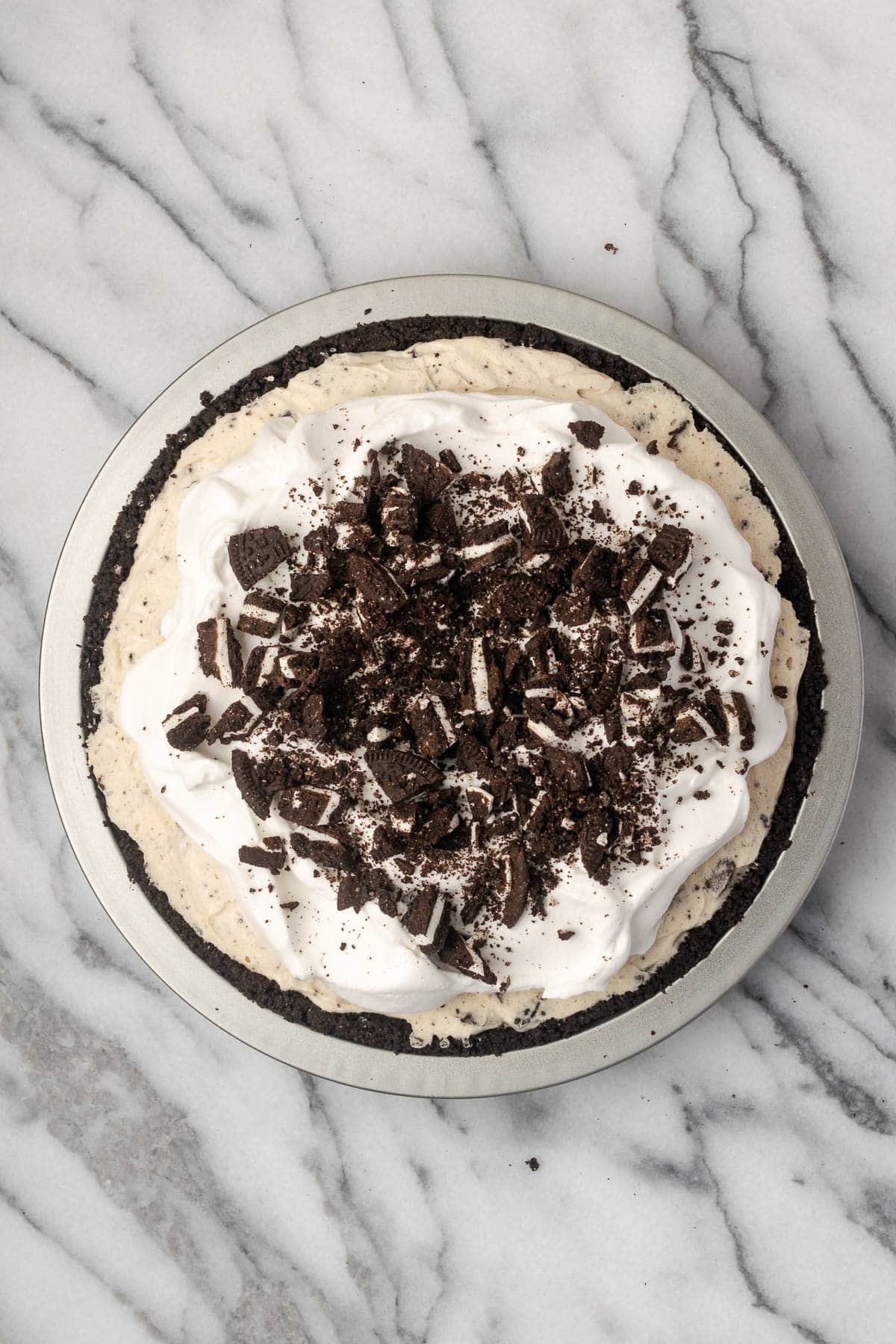 An Oreo pie topped with whipped cream and chopped Oreo cookies.
