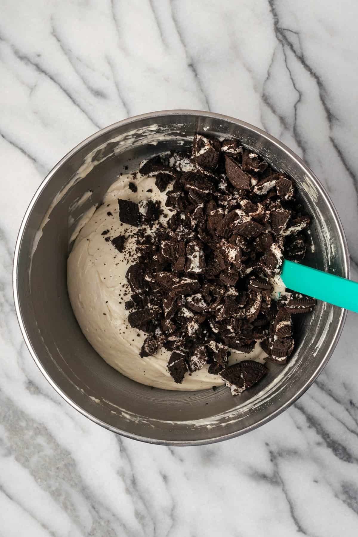 Chopped Oreo cookies being folded into the pie filling.