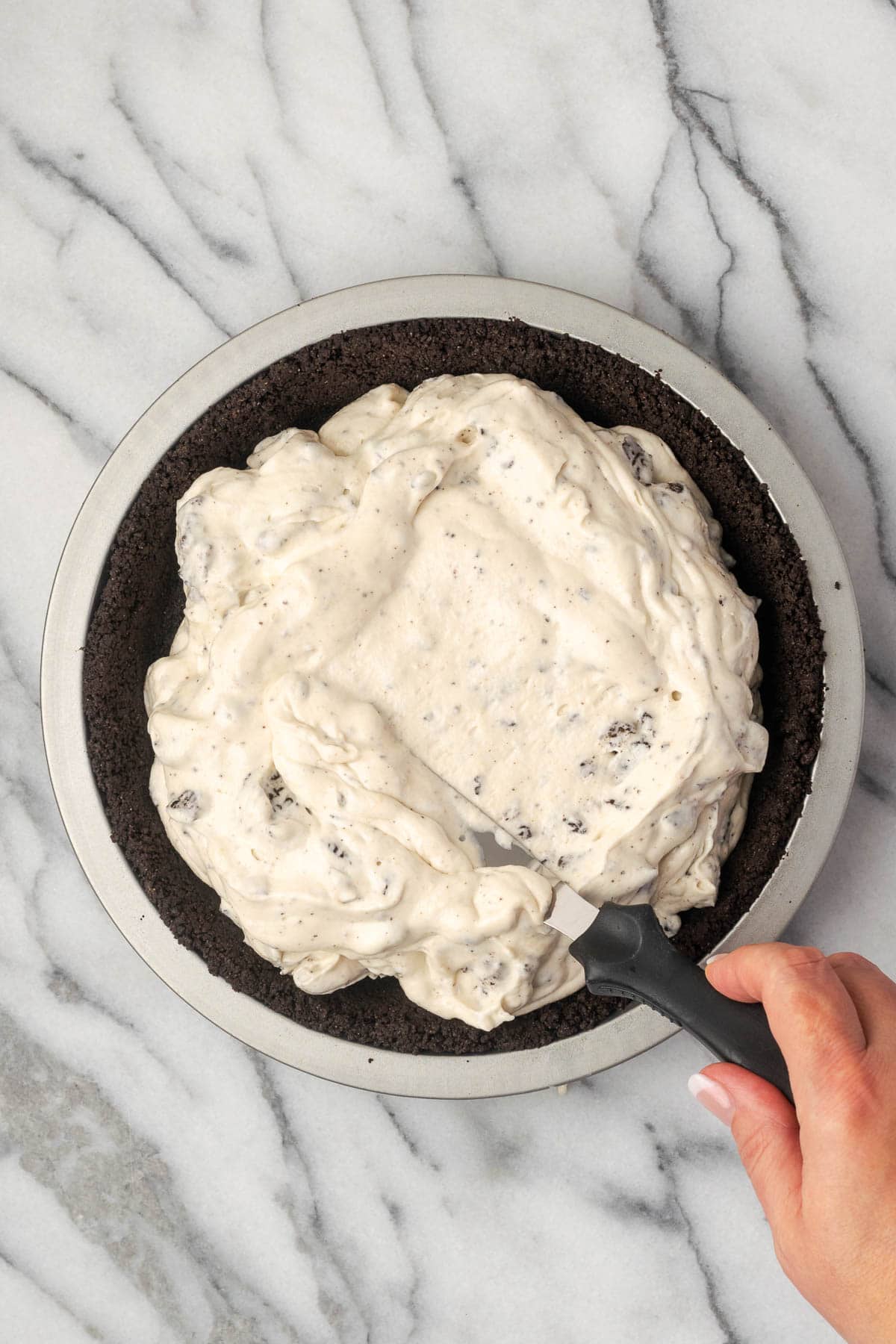 Oreo pie filling being spread in an Oreo pie crust.