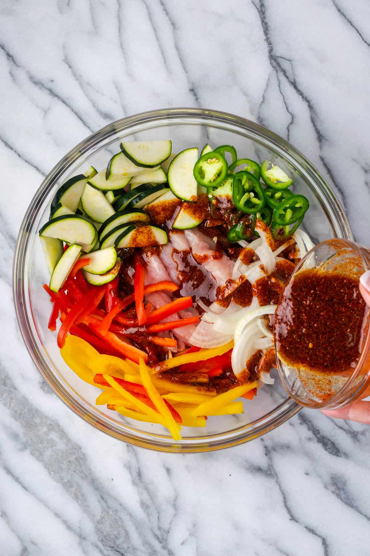 Chicken, bell peppers, onion, zucchini and jalapeno in a large bowl with fajitas marinade. 