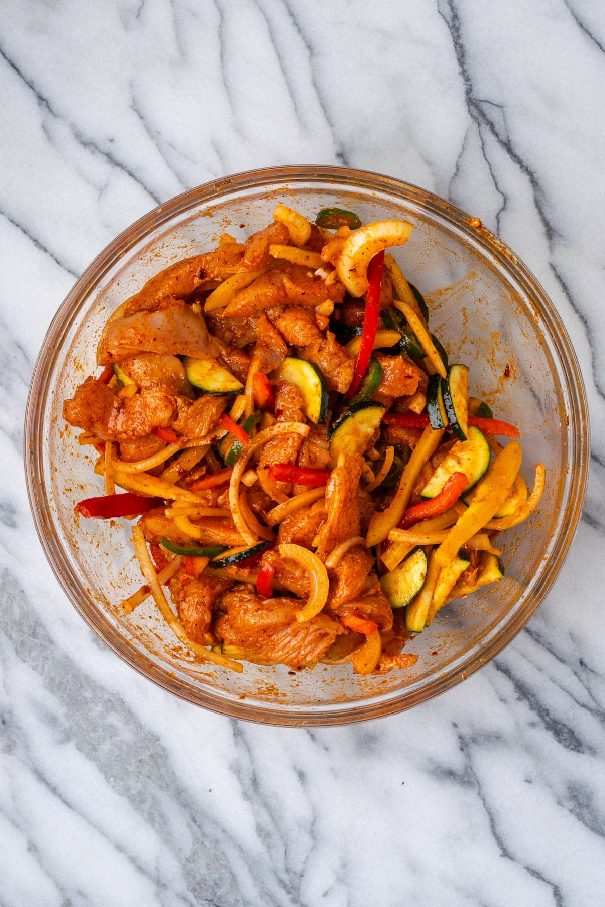 Chicken fajitas marinating in a large bowl. 