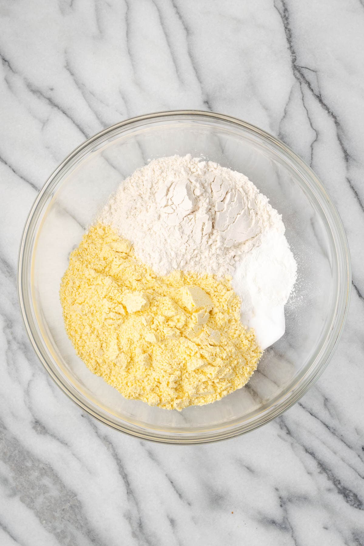 Cornmeal, flour, sugar, baking powder, baking soda, and salt combined in a large mixing bowl.