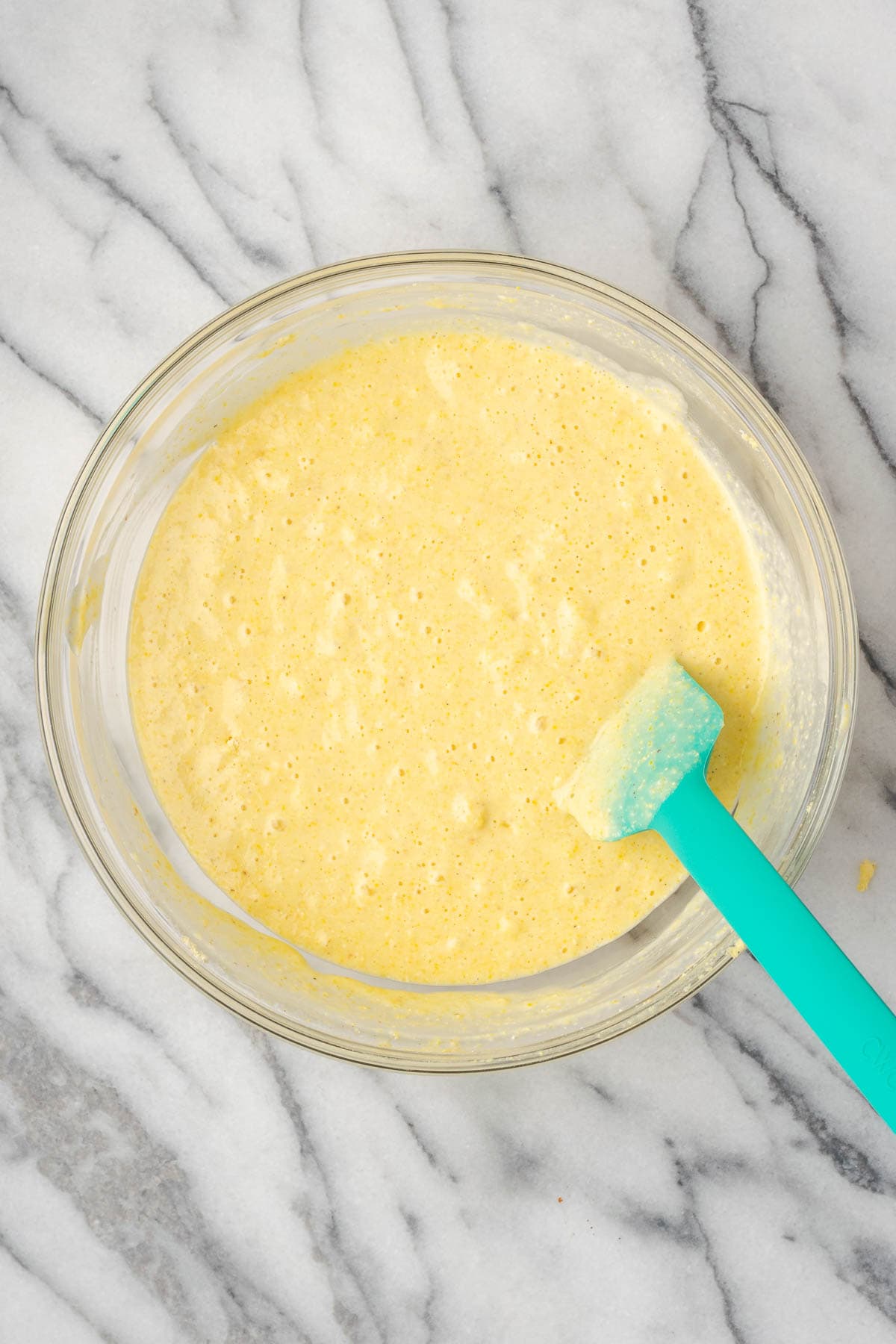 A bowl of cornbread batter resting on a marble counter.