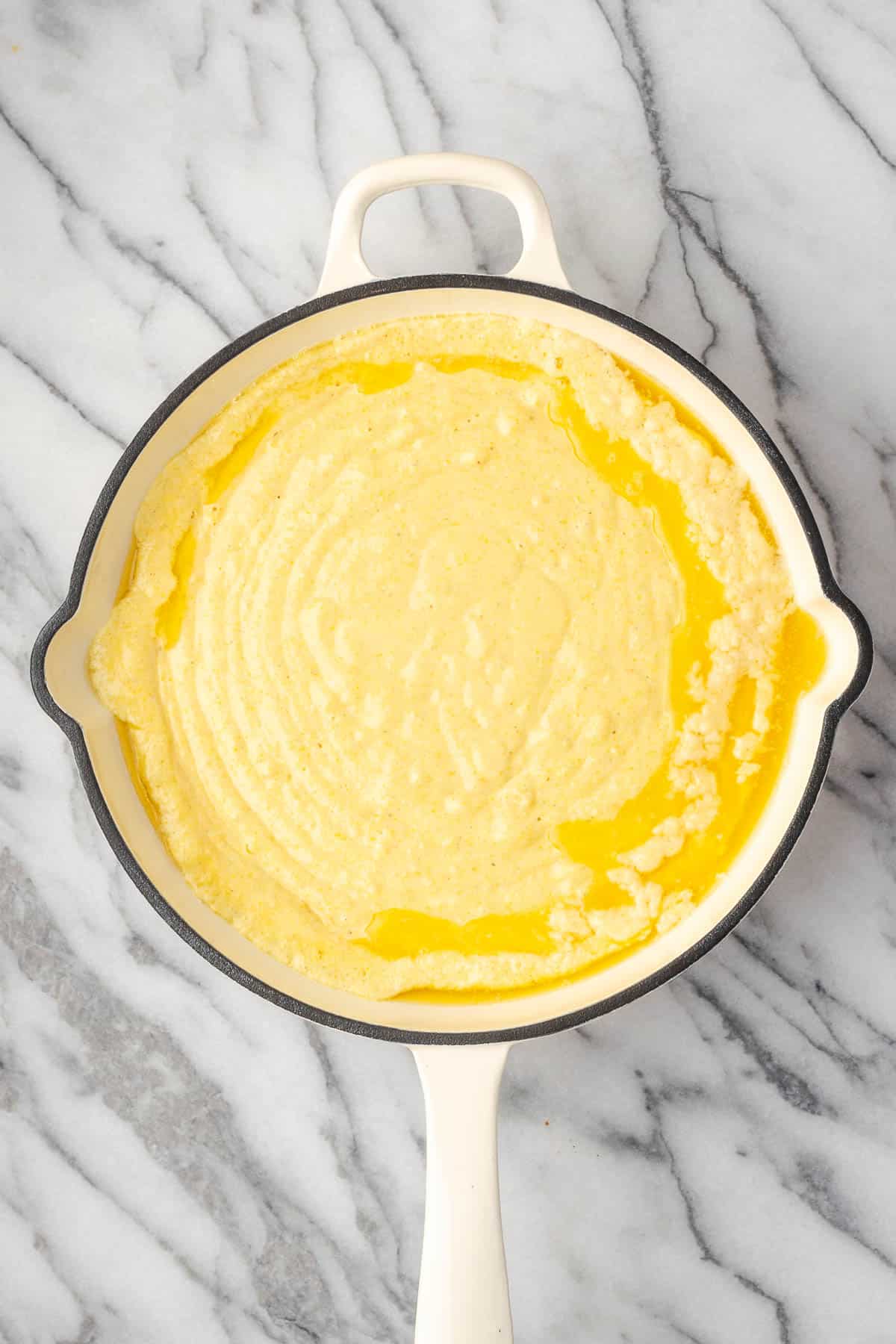Cornbread batter poured into a skillet of melted butter.