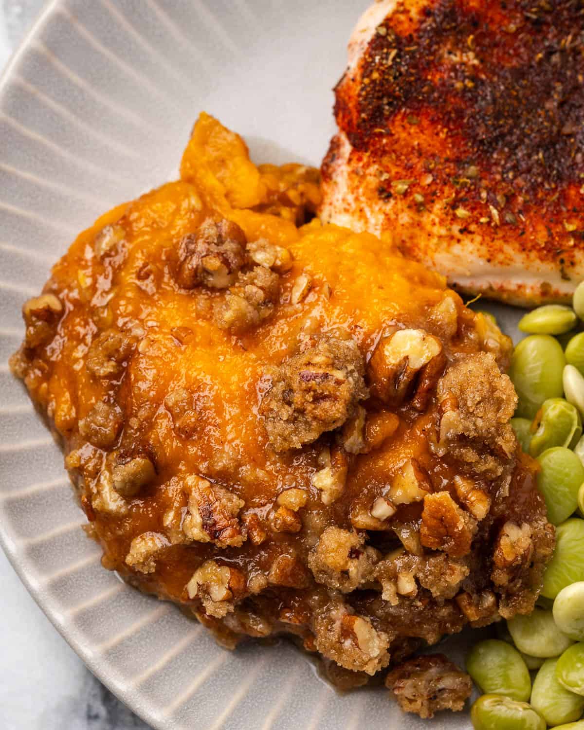 Sweet potato casserole served with chicken and lima beans on a dinner plate.