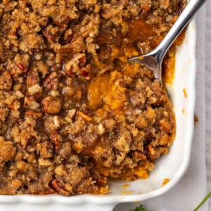 A serving spoon scooping into a pan of sweet potato casserole.