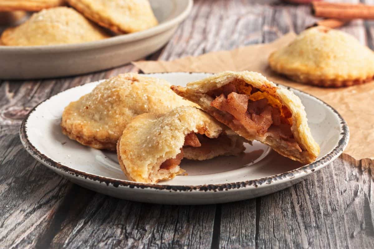 Two apple pie cookies stacked on a small plate.