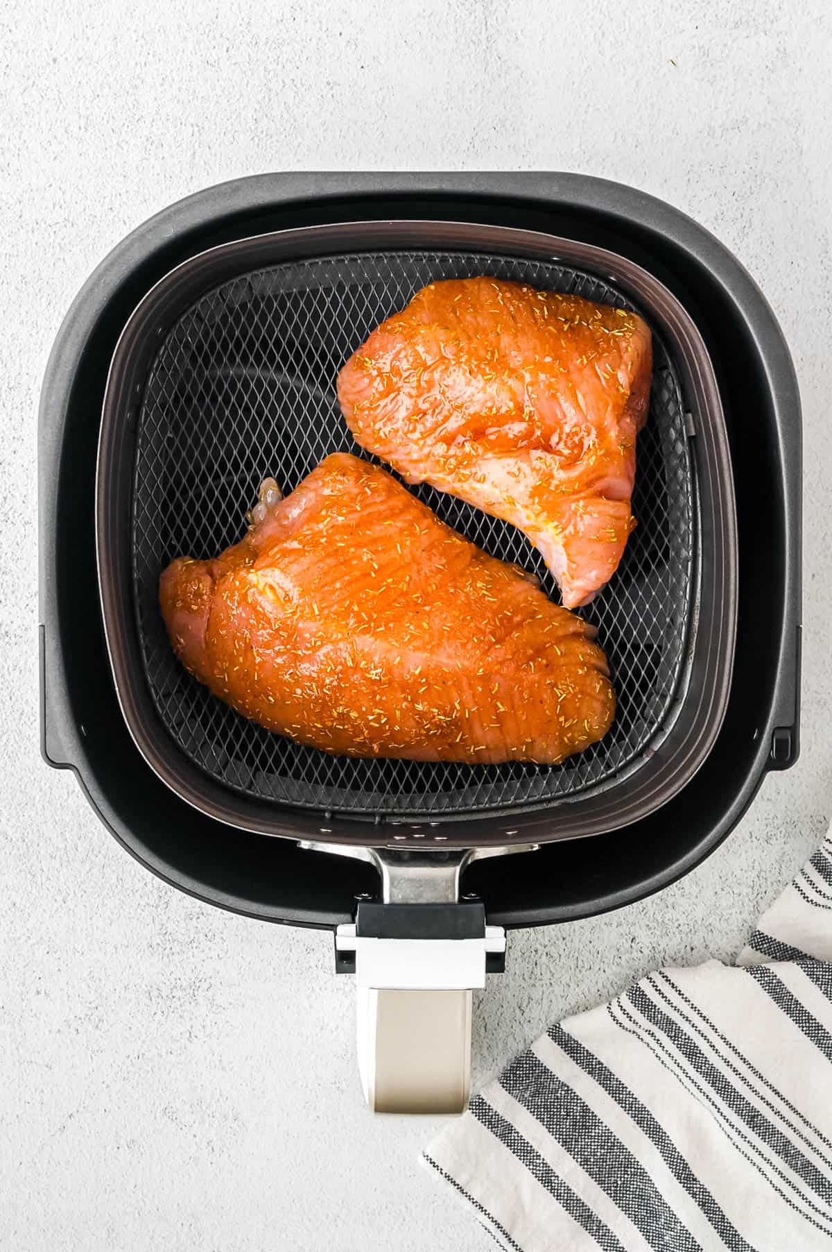 Two pieces of turkey tenderloin in an air fryer basket.