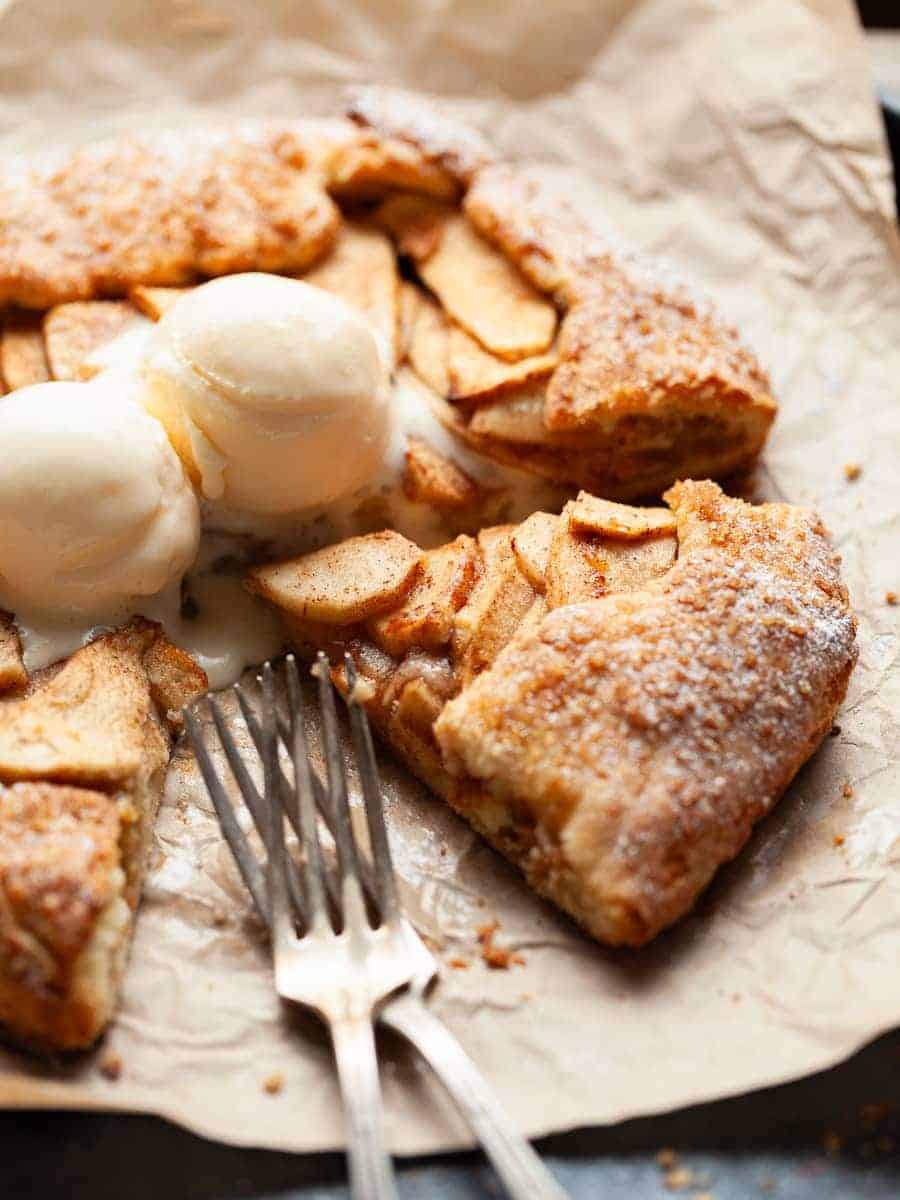 An apple galette topped with vanilla ice cream sitting on a piece of brown paper.
